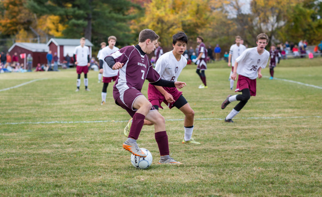 Chris Bennett trips up an Orono defender. Photo by Tate Yoder